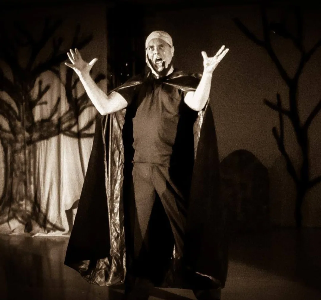 Mark Novak performing in a cape on a theatrical set