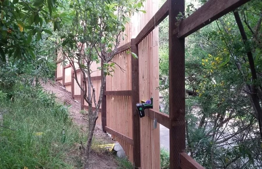 Rear framing of a cedar privacy fence on a hillside