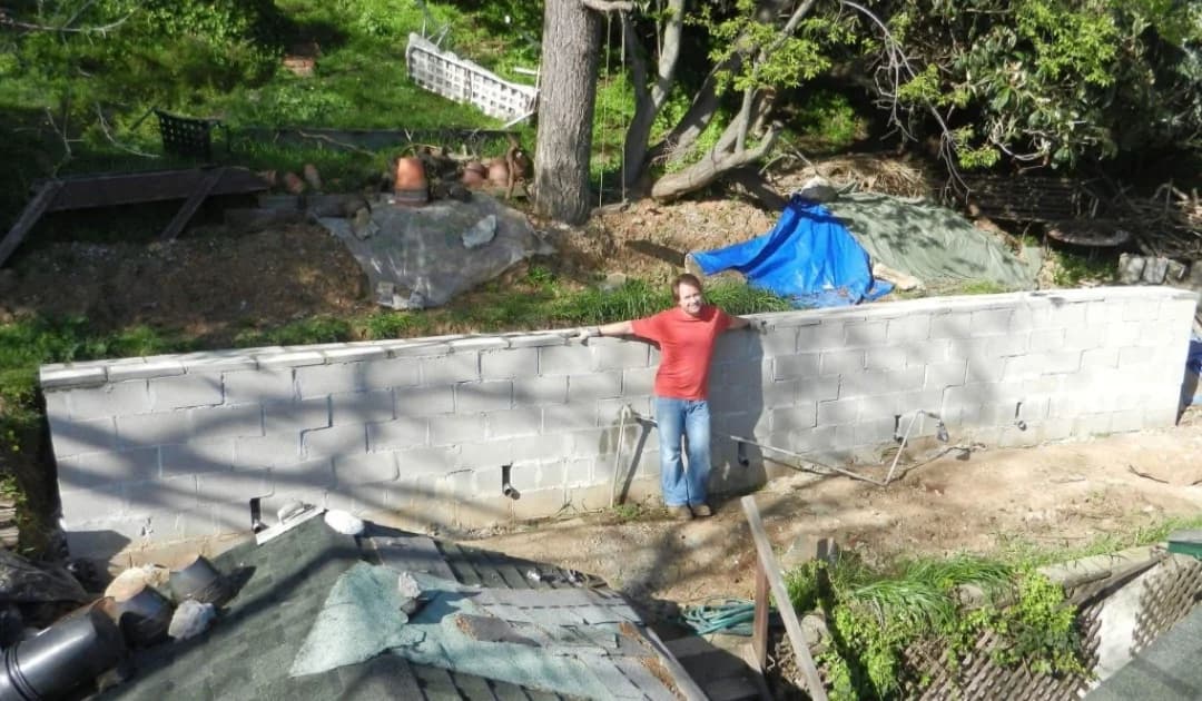 Mark Novak standing beside a completed masonry retaining wall